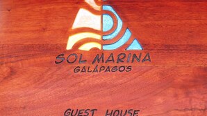 A wooden sign with the text "SOL MARINA GALÁPAGOS GUEST HOUSE". - GALAPAGOS CASA MARINA (Puerto Ayora)