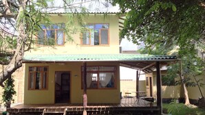 A two-story house with a green roof, wooden porch, and a small garden area. - GALAPAGOS CASA MARINA (Puerto Ayora)