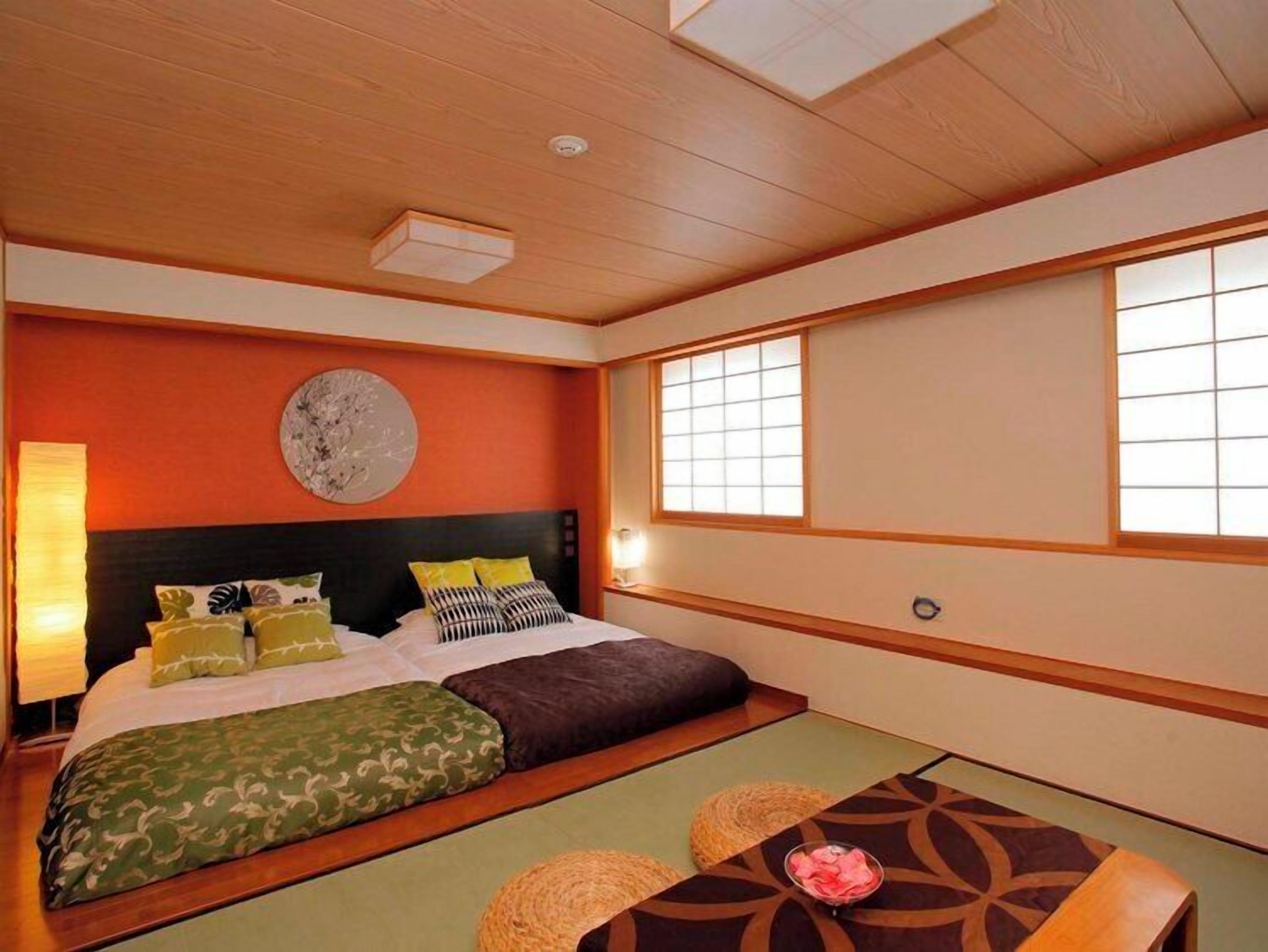 Une chambre de style japonais traditionnel, avec un sol recouvert de tatamis, un lit bas en bois et des paravents en papier de riz (shoji).