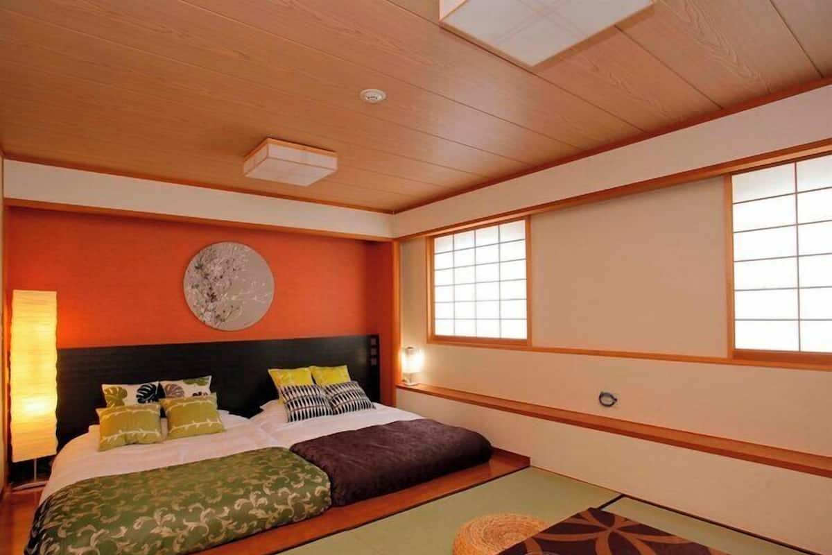 Een traditionele Japanse slaapkamer met tatami vloeren, een laag houten bed en shoji schermen.