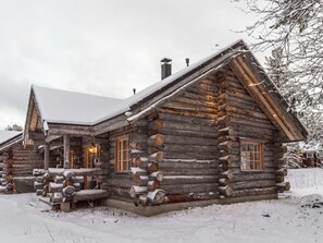 A log cabin with a steeply pitched roof, large windows, and a porch area.