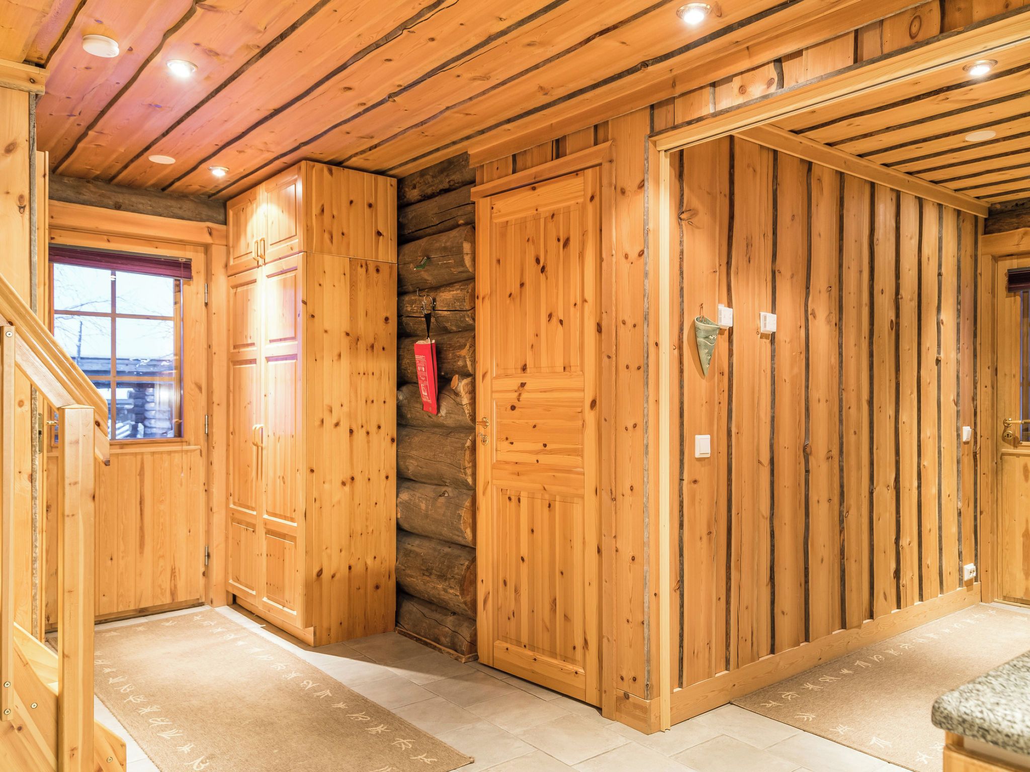 A wooden interior with a stone wall, wooden doors, and a window.