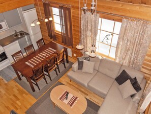 Accogliente interno di una baita con zona pranzo, divano e angolo cottura.