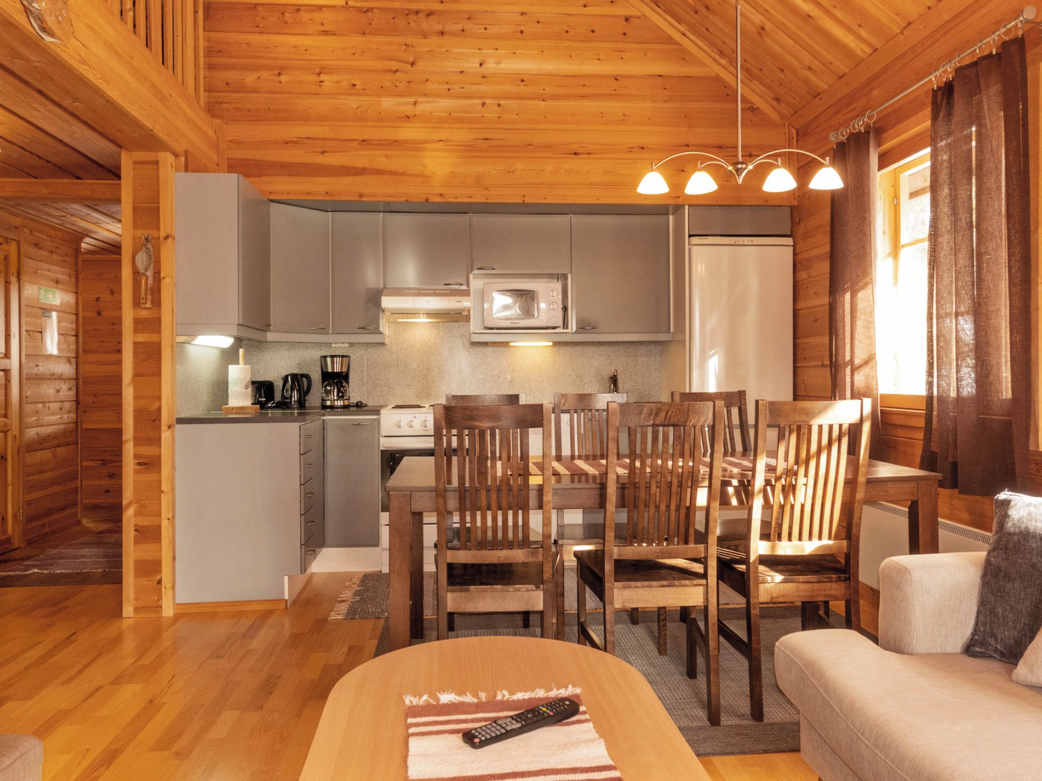 Interior acogedor de una cabaña con comedor, cocina y sofá.