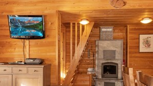 A wooden cabin interior with a fireplace, a television mounted on the wall, and a wooden staircase. - Mervinrinne by Interhome (Sodankylä)