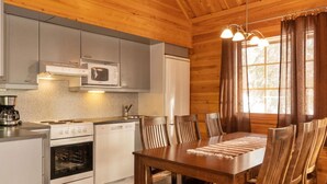 A modern kitchen with a stove, oven, microwave, and sink. There is a dining table with chairs and a rug. - Mervinrinne by Interhome (Sodankylä)
