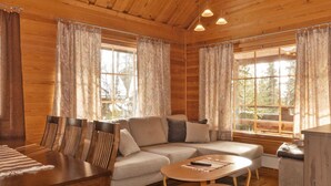 A cozy cabin interior with a wooden dining table, sofa, and a small coffee table. - Mervinrinne by Interhome (Sodankylä)