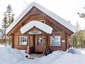 A wooden cabin with a snow-covered roof, a wooden door, and windows. There is a sign above the door and a number '25' on the wall. - Mervinrinne by Interhome (Sodankylä)