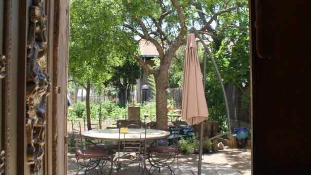 An open door leading to an outdoor patio with a table and chairs, surrounded by trees. - Mas de Bellegou B&B (Portiragnes)