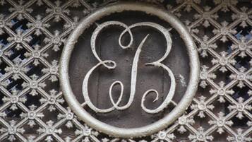 A decorative metal grille with a circular emblem featuring a stylized letter 'B'.