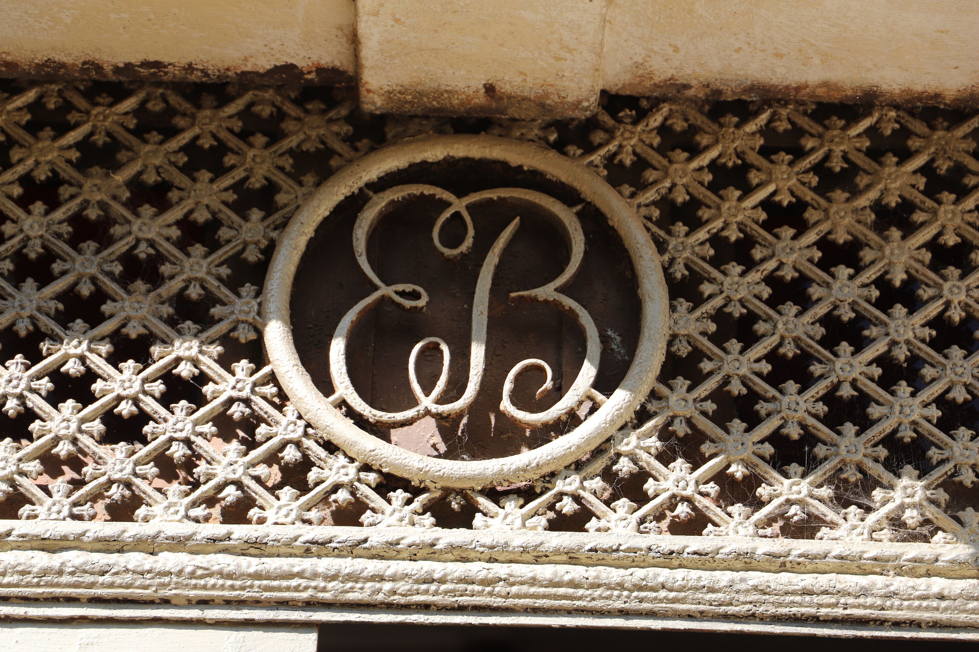 A decorative metal grille with a circular emblem featuring a stylized letter 'B'.