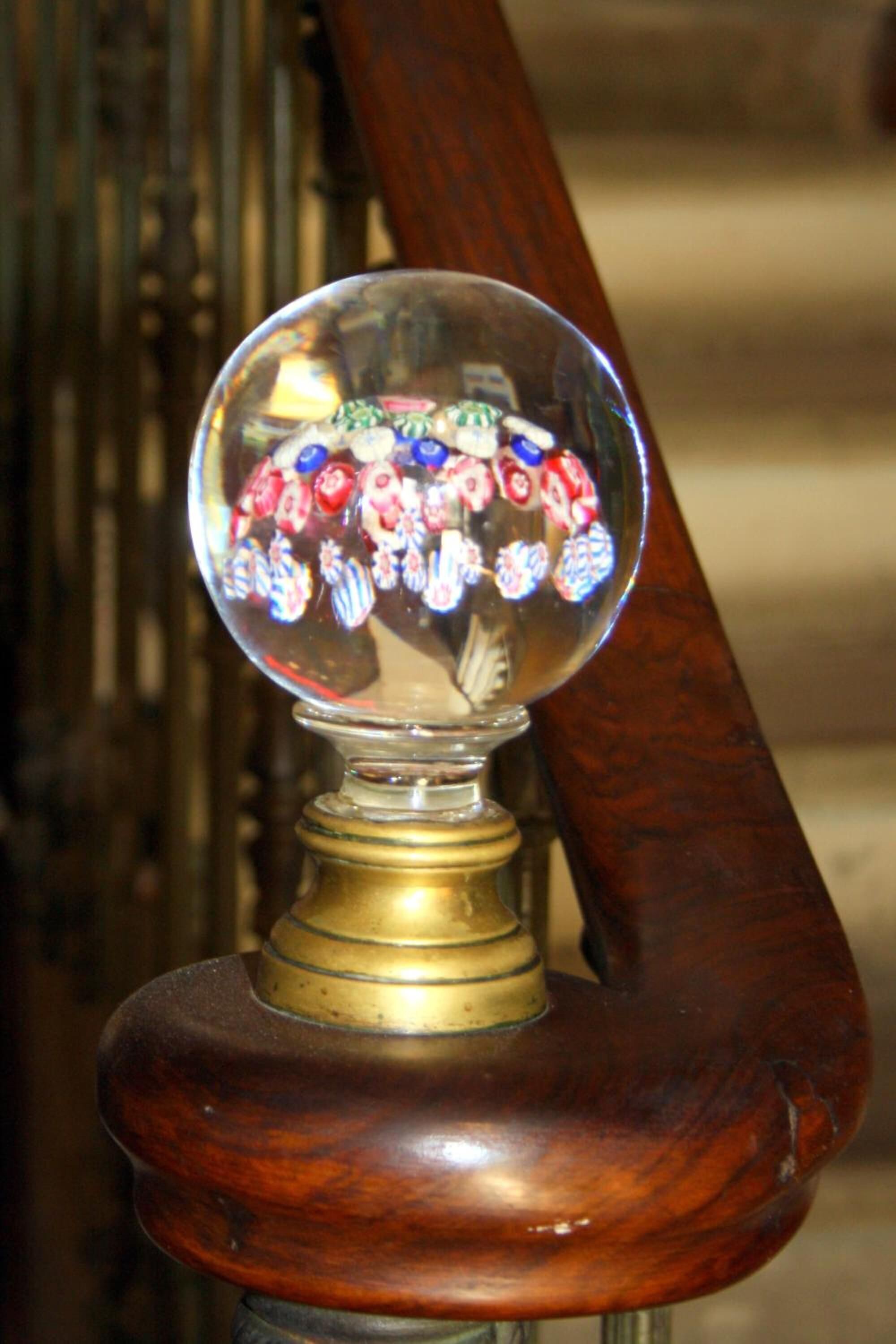 A wooden chair with a brass base and a glass ornament containing colorful flowers.