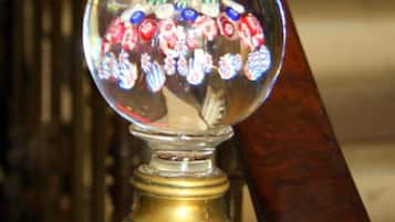 A wooden chair with a brass base and a glass ornament containing colorful flowers.