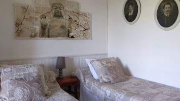 Un dormitori amb dos llits, una tauleta de nit i una estàtua de Buda penjada a la paret.