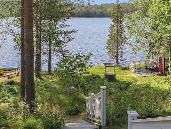 A lakeside property with a wooden deck, a gazebo, and a small cabin.