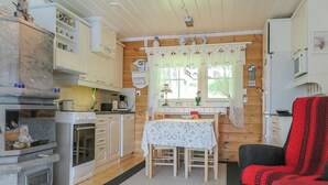 Una cocina compacta con armarios de madera, una mesa de comedor y una silla roja.