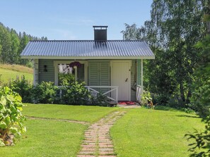 Ein kleines, eingeschossiges Haus mit einem Metalldach, einer Veranda und einem Ziegelweg, der zum Eingang führt.