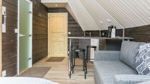 Une pièce compacte et moderne, dotée d’une kitchenette, d’un canapé et d’une porte donnant sur une autre pièce.
