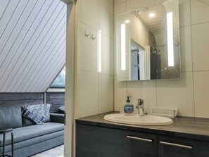 A modern bathroom with a large mirror, a sink, and a shower area. - Arctic light hut by Interhome (Inari)