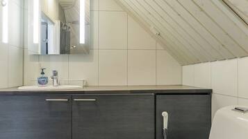 Une salle de bain moderne avec un meuble-lavabo foncé, un miroir et une douche.