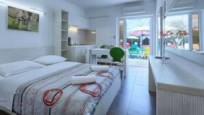 Ein modernes Schlafzimmer mit Bett, Nachttischen, Schreibtisch und Blick ins Freie.