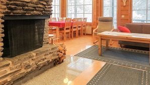 A cozy cabin interior with a stone fireplace, wooden dining table, and chairs.