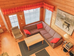 A cozy cabin interior with a sectional sofa, a wooden coffee table, a chair, and a fireplace. - Riekkoluosto by Interhome (Sodankylä)