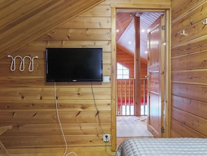 A wooden cabin with a mounted television, a bed, and a door leading to an outdoor area. - Riekkoluosto by Interhome (Sodankylä)