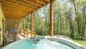 A hot tub with wooden deck and lounge chairs, surrounded by a forested area. - Bobcat Bluff-Hocking Hills State Park-Covered Hot Tub-Firepit-Pool Table-WiFi  (Logan)