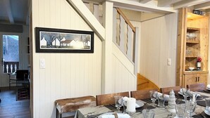 A dining area with a wooden staircase, a framed picture on the wall, and a wooden cabinet with glassware. - Chalet Le Renard Du Lac- close to the Chavanne piste and lake (Les Gets)