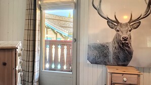 A room with a wooden dresser, a wooden cabinet, a mounted deer head, a door with a view to the outside, and a window with curtains. - Chalet Le Renard Du Lac- close to the Chavanne piste and lake (Les Gets)