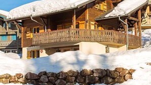 A wooden chalet with a balcony, surrounded by snow. - Chalet Le Renard Du Lac- close to the Chavanne piste and lake (Les Gets)