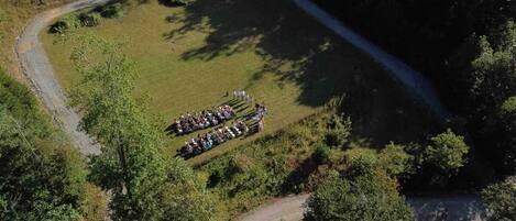 An aerial view of a circular gathering of people in a grassy field with trees around.