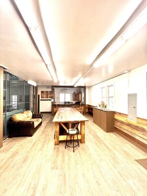 A spacious room with a long wooden table, a sofa, and a kitchen area in the background. - " Casa Grande" Hot Tub_ Indoor Basketball + Movie (Brevard)