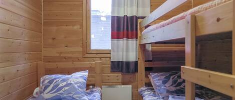Een blokhut met twee stapelbedden, een raam met gordijnen en een radiator.