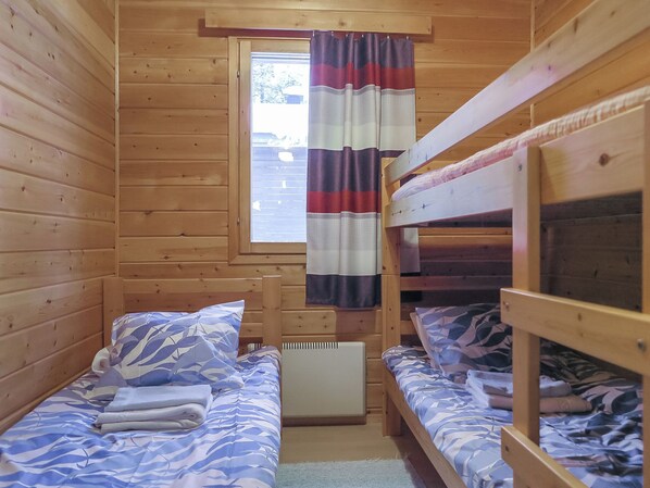 Eine Hütte mit zwei Etagenbetten, einem Vorhangfenster und einer Heizung.