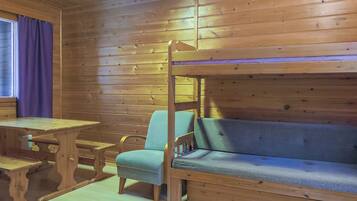 Ein Holzblockhaus-Innenraum mit einem Etagenbett, einem Tisch und einem Stuhl.