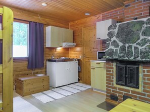Eine kleine Küche mit Holzausstattung, einem Steinkamin und einem Fenster mit Vorhängen.