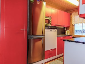 A kitchen with red cabinets, a stainless steel refrigerator, a microwave, and a dishwasher. - Ylikyrön mökki by Interhome (Enontekiö)