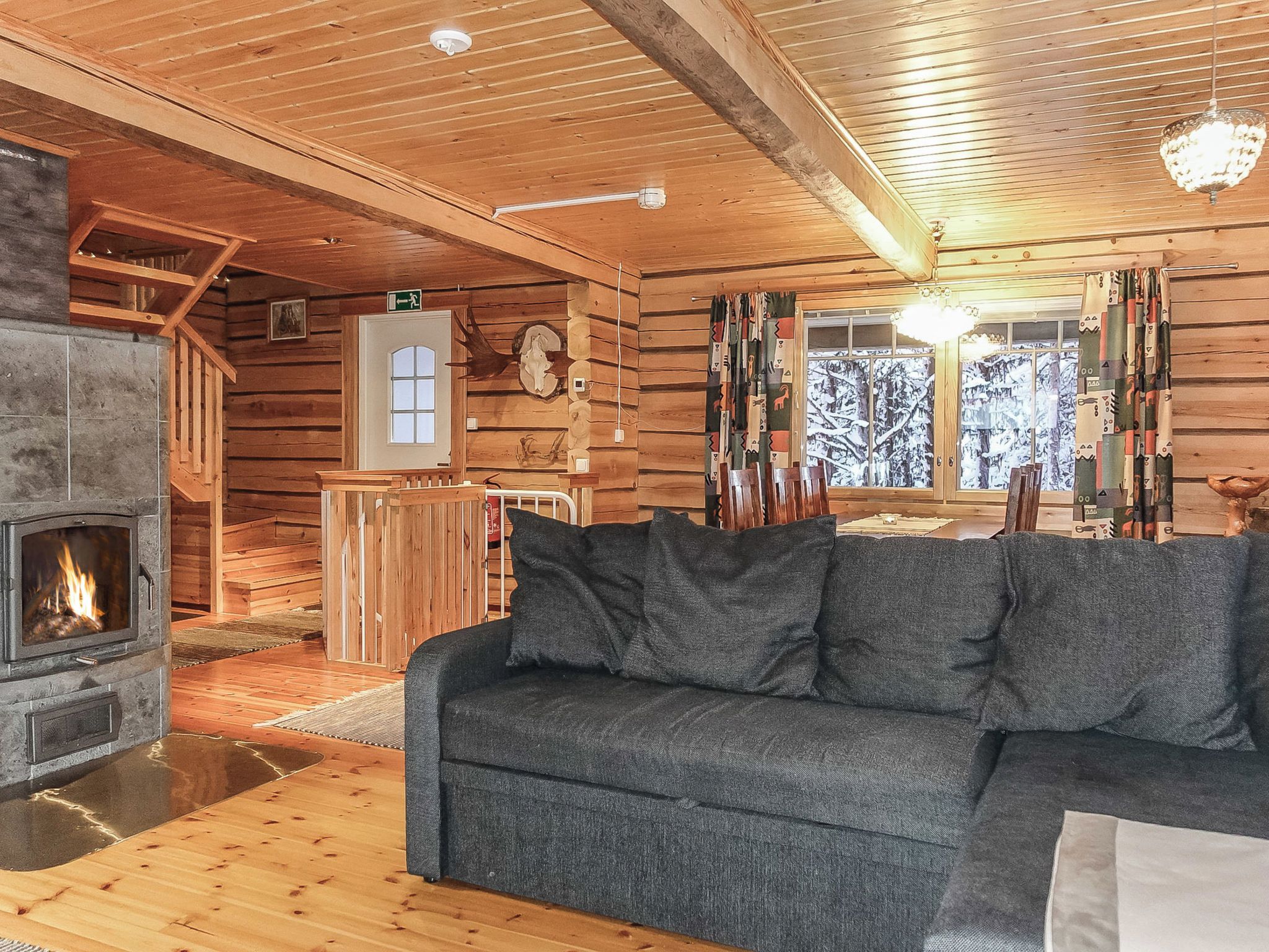 Ein Blockhaus-Interieur mit Kamin, Holzwänden, einer Couch und einem Essbereich.