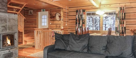 L’intérieur d’une cabane en rondins, avec une cheminée, des murs en bois, un canapé et un coin repas.