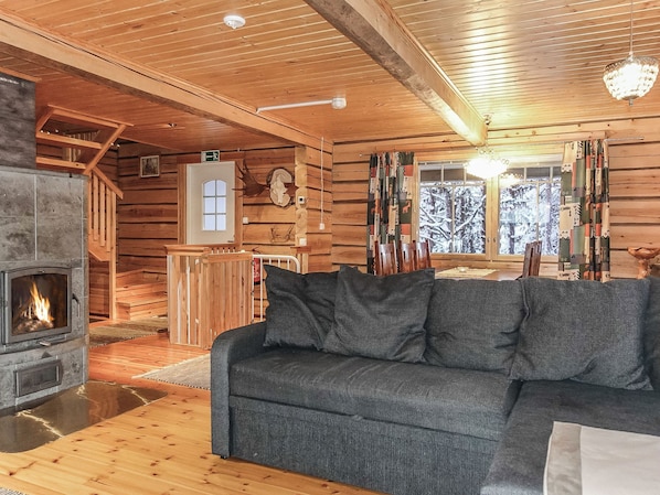 A log cabin interior with a fireplace, wooden walls, a sofa, and a dining area. - Ylikyrön mökki by Interhome (Enontekiö)
