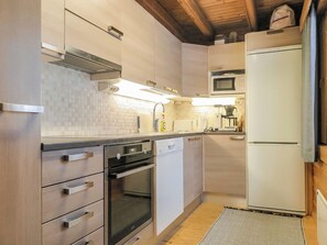 A modern kitchen with stainless steel appliances, wooden cabinets, and a tiled backsplash. - Keromaja by Interhome (Inari)