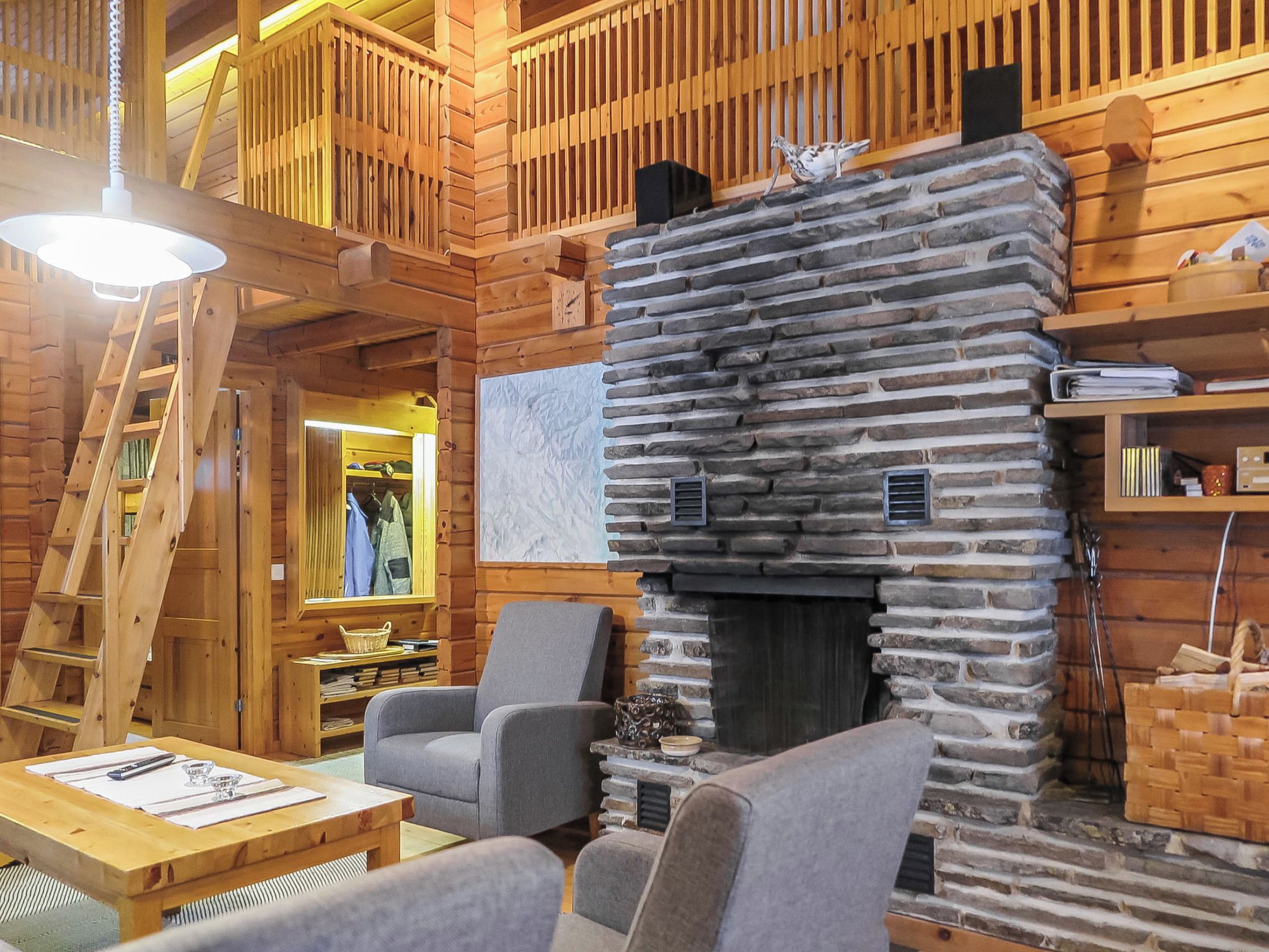 A cozy interior with a stone fireplace, wooden furniture, and a lofted sleeping area.