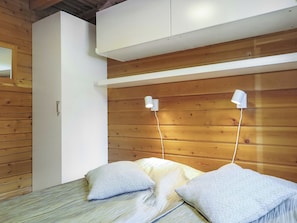 Une chambre à coucher avec un lit, deux lampes de chevet, une tête de lit en bois et une armoire blanche.