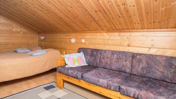 Een gezellig chaletinterieur met een houten plafond, een bed, een bank en een kamerbreed tapijt.