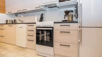 A modern kitchen with white cabinetry, a built-in oven, a microwave, and a coffee maker.