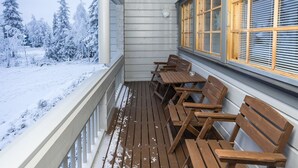 A wooden deck with benches, a railing, and a view of a snowy landscape.