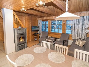 A cozy cabin interior with a fireplace, wooden walls, a television, and a sofa set. - Rukannaava 1b (12) by Interhome (Kuusamo)