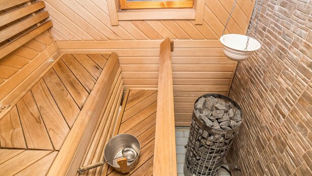 A sauna with wooden benches, a window, a hanging basin, and a charcoal filter.